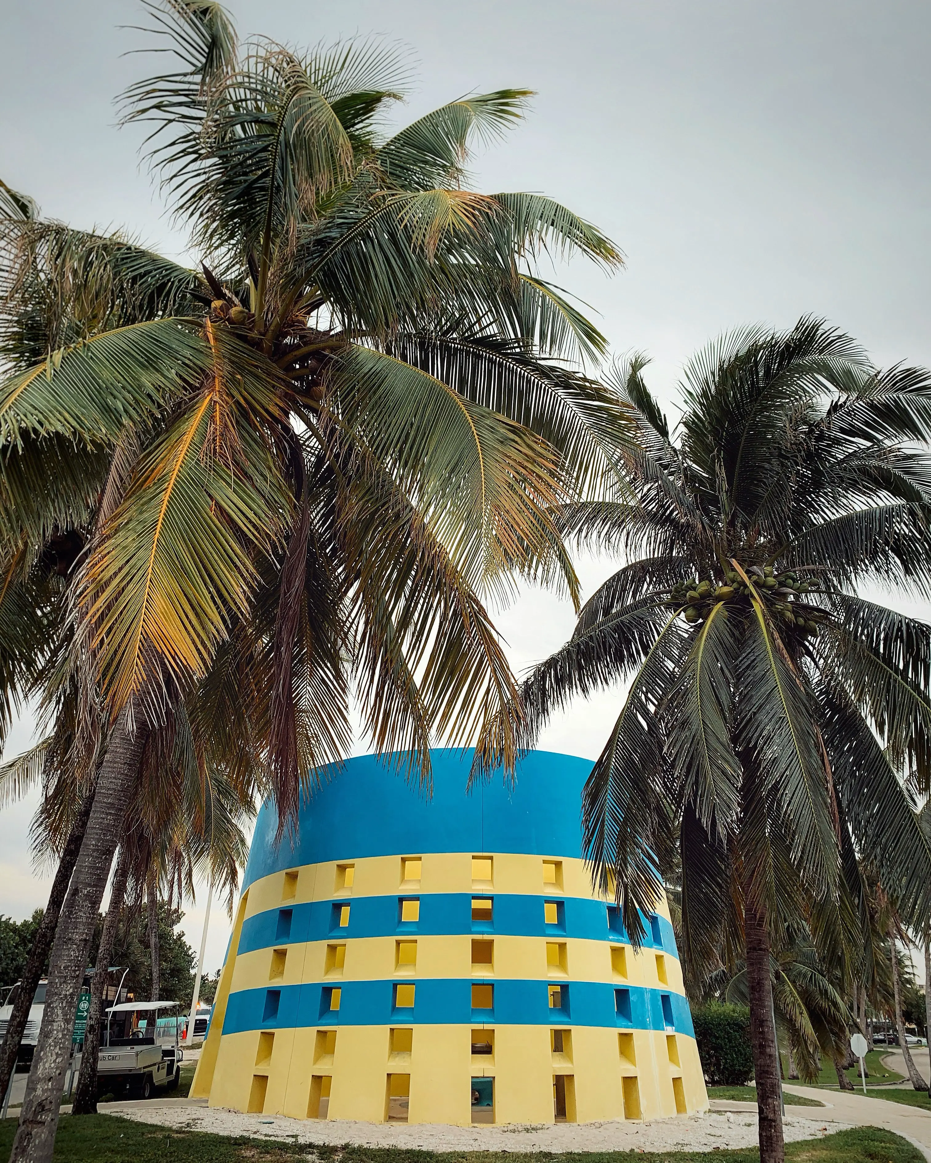 Vibrant Miami Beach scene with blue umbrellas and city skyline under a sunny sky.