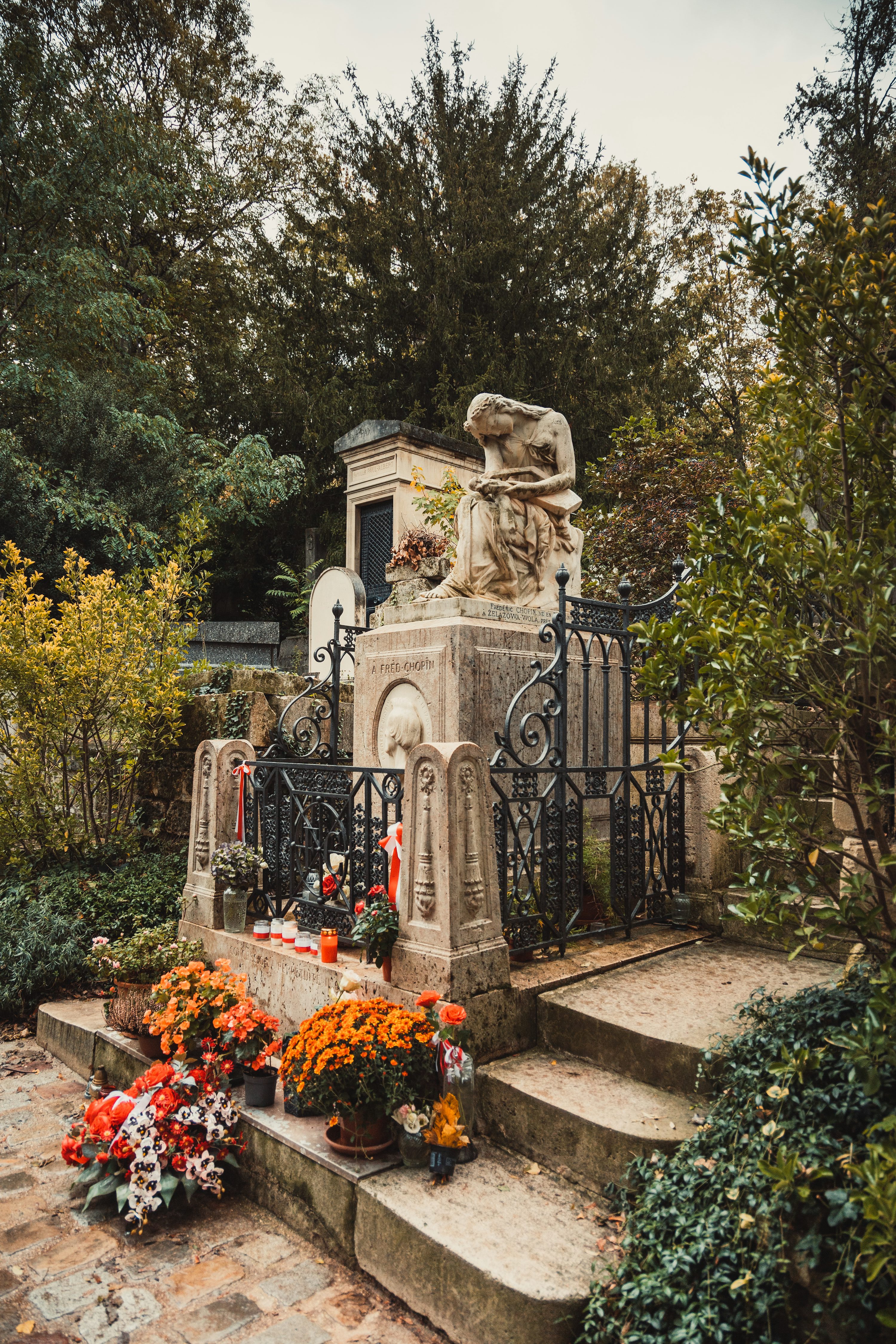 a cemetery with a statue and flowers in the foreground