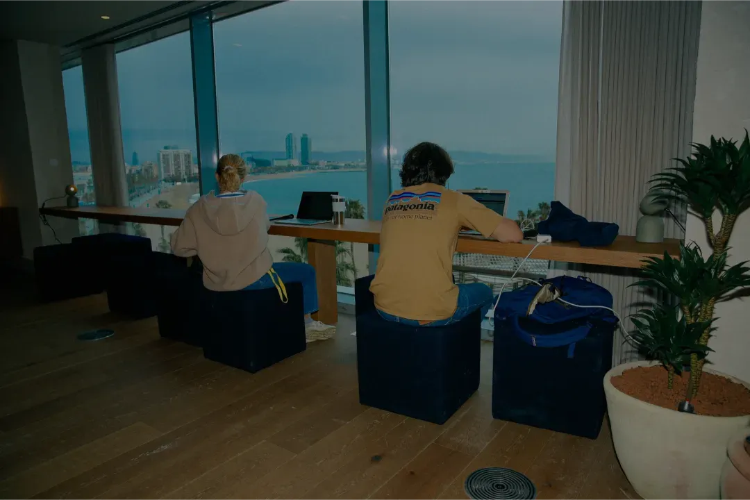 Two Norrsken members working at the counter with Barcelona skyline and sea behind them